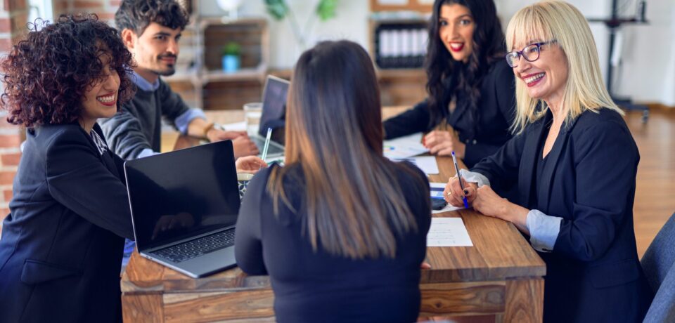 Group of business workers smiling happy and confident. Working together with smile on face  using laptop and speaking at the office